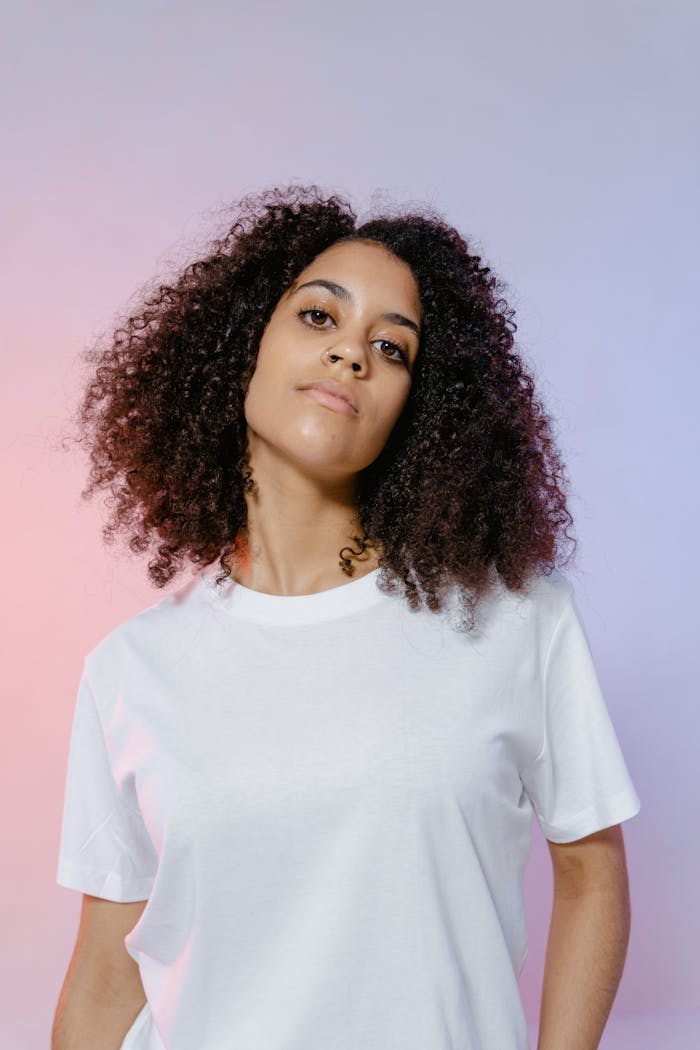The Art of Drawing Readers In: Your attractive post title goes here Portrait of a young woman with curly hair posing in a white shirt against a pastel background.